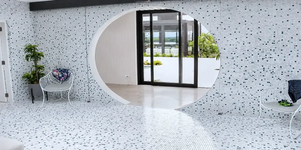 Curved mosaic tile installation around circular bathhouse opening.