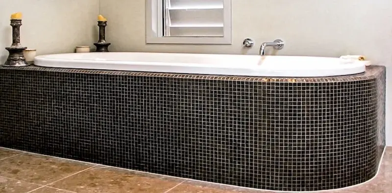 Curved bath surround finished in small-format mosaic