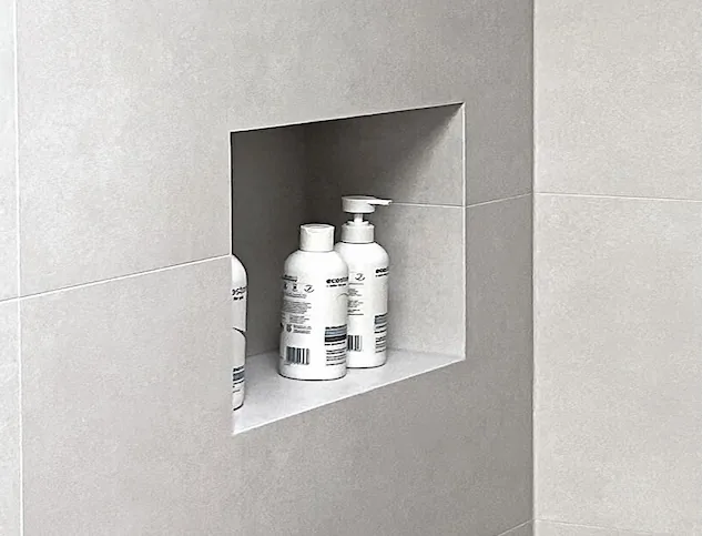 Recessed shower niche cut into large-format porcelain tiles with mitred edges
