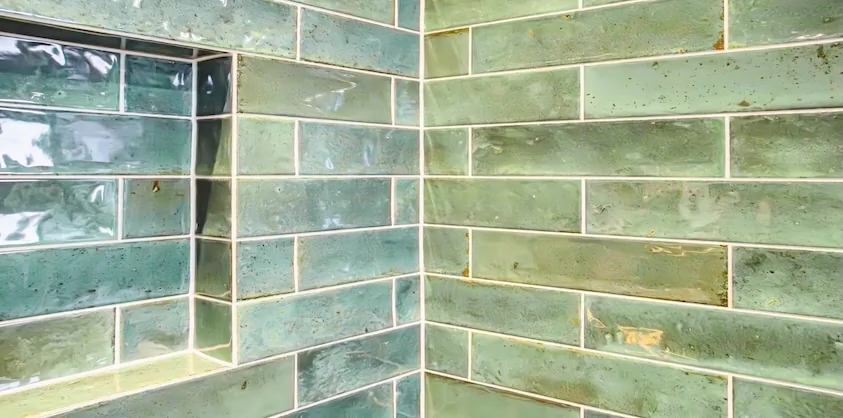 Glazed green subway tiles aligned through a shower niche and internal corner