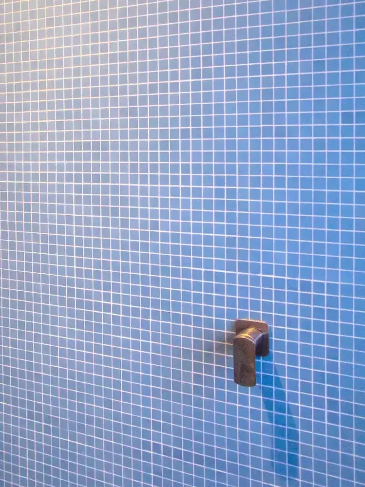 Curved mosaic tile installation around circular bathhouse opening.